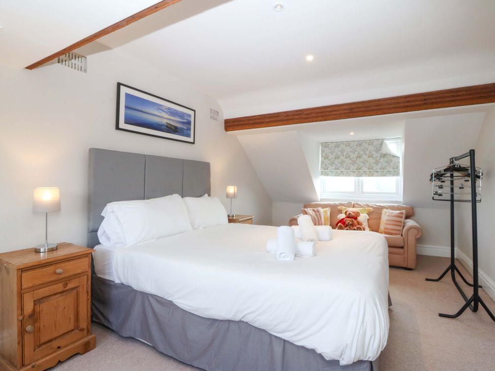 A bedroom with a bed and sofa at Bryniau in Morfa Nefyn
