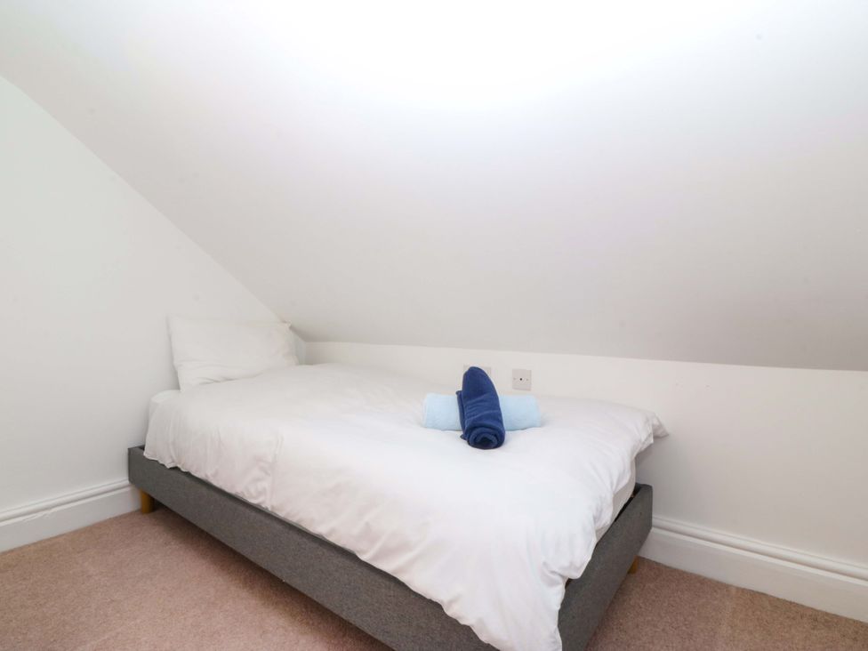 A bedroom with a bed and towels at Bryniau Morfa Nefyn