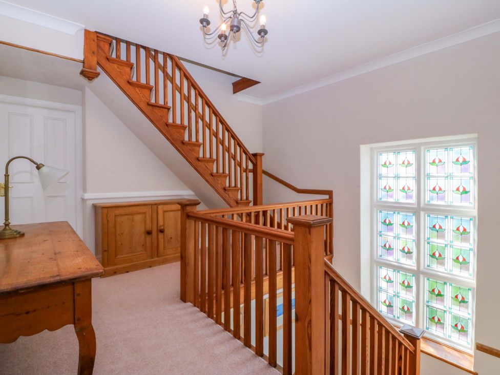 A staircase with wooden handrail and stained glass window at Bryniau Morfa Nefyn