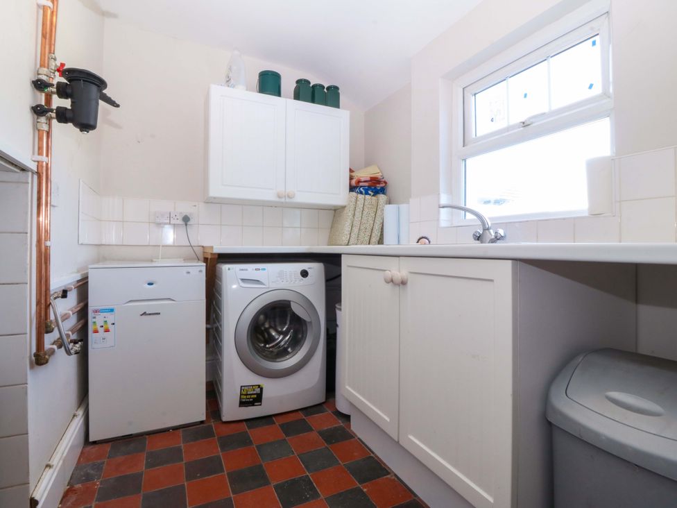 A laundry room with a washing machine and refrigerator at Bryniau in Morfa Nefyn