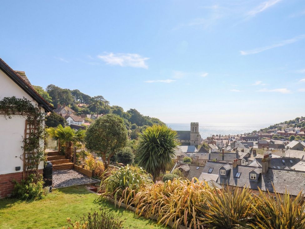 A view of a house with a garden and sea in the background at Devona Beer
