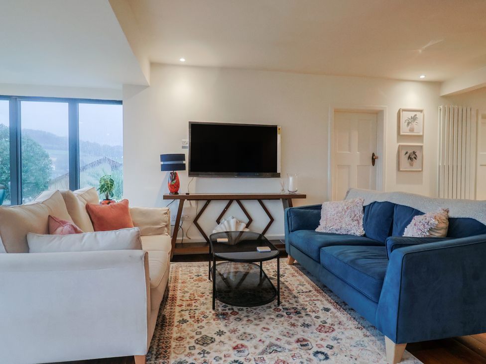 A living room with sofas and a television at Devona in Beer