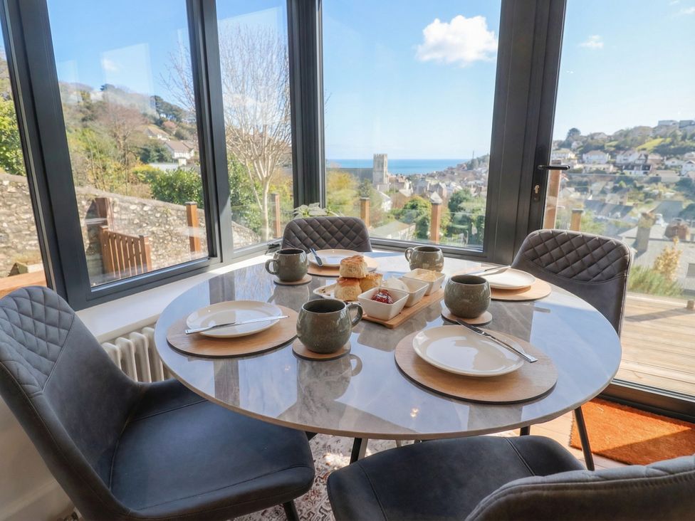 A dining room with a round table set for tea at Devona in Beer