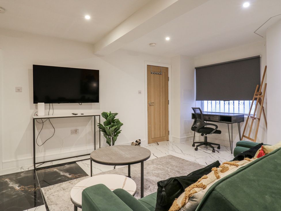 A living room with a television, desk, and couch at 2A Ruby Street Southwark, London