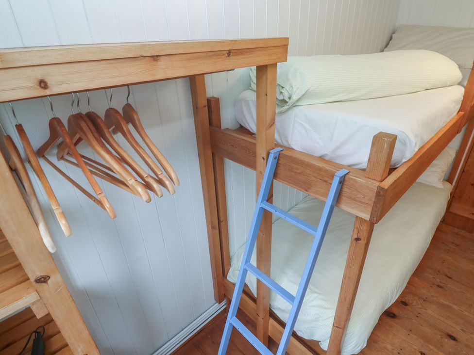 A bunk bed with wooden hangers and a ladder at Pleasans in Hayle