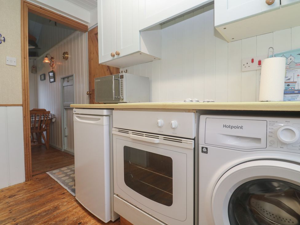 A kitchen with a microwave, oven, washing machine, and refrigerator at Pleasans in Hayle