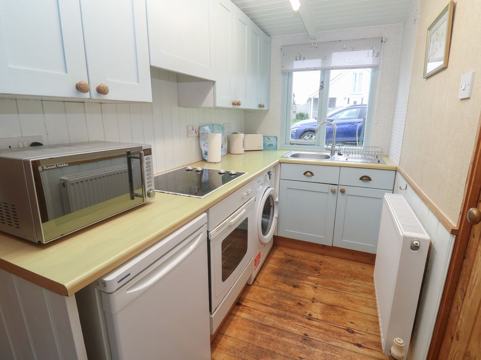 A kitchen with a microwave and washing machine at Pleasans in Hayle