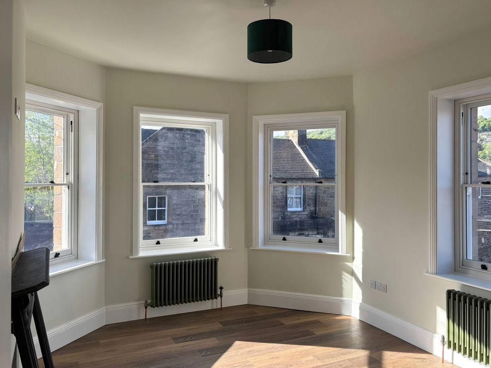 A living room with windows and a radiator at Holt Hall - First Floor Apartment in Matlock