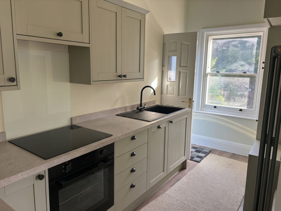 A kitchen with cabinets, sink, and cooker at Holt Hall - First Floor Apartment in Matlock