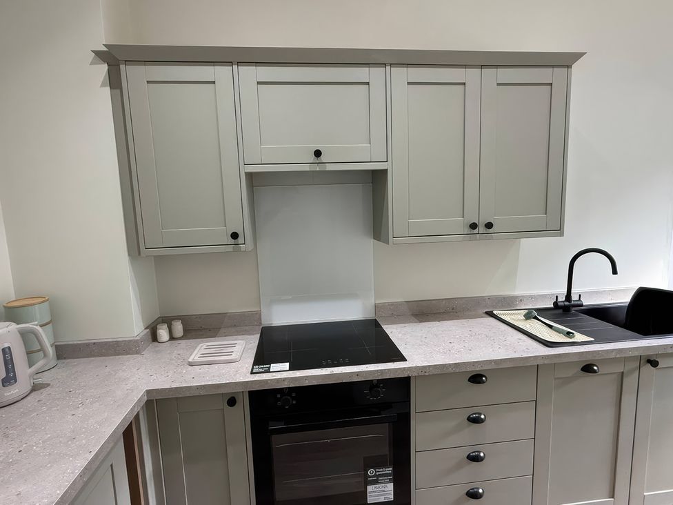 A kitchen with cabinets, stove, sink, and kettle at Holt Hall - First Floor Apartment in Matlock