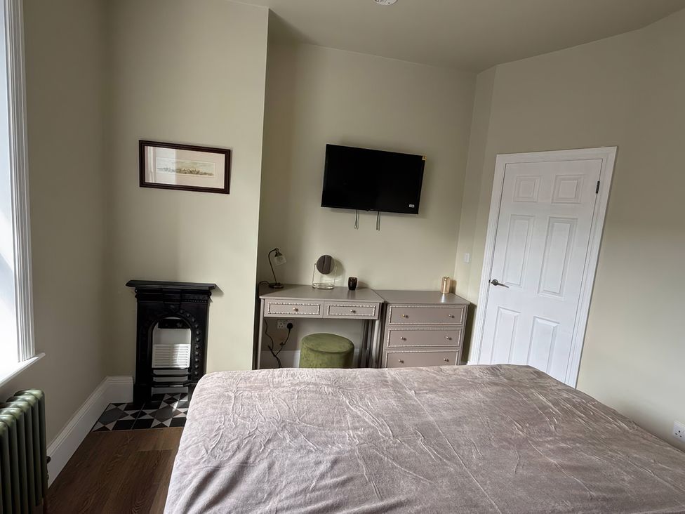 A bedroom with a bed, desk, television and fireplace at Holt Hall - First Floor Apartment in Matlock