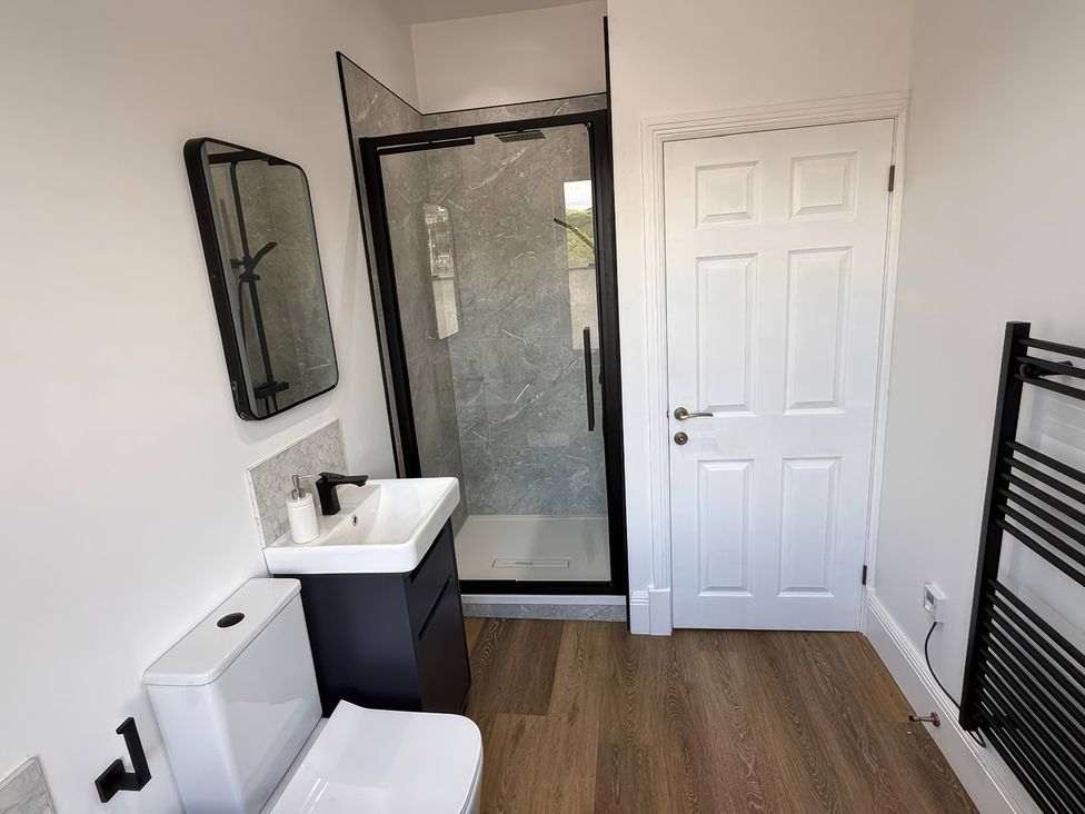 A bathroom with a sink, toilet, shower, and towel rack at Holt Hall - First Floor Apartment in Matlock