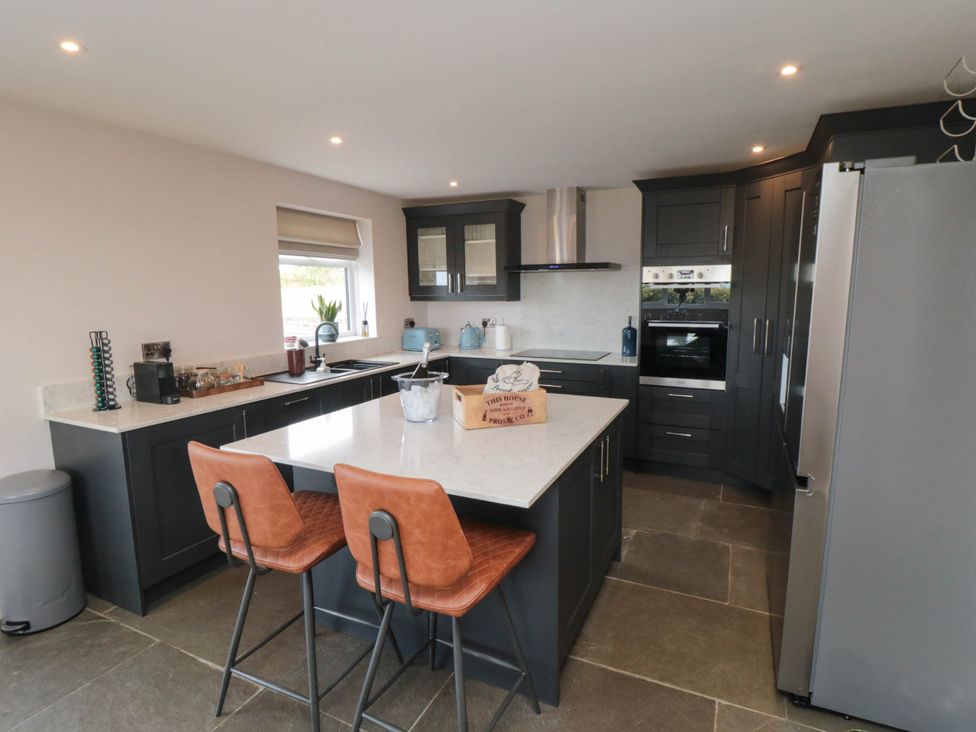 A kitchen with an island and bar stools at Westholme Lodge in Thirsk