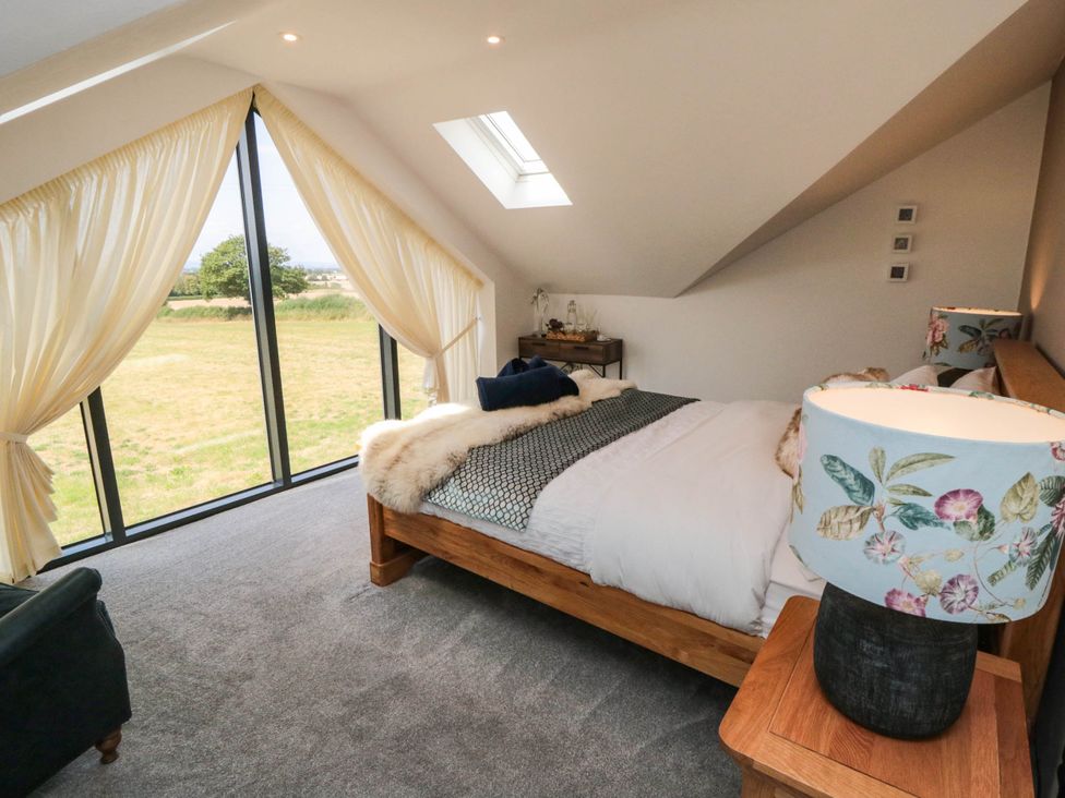 A bedroom with a bed and large windows at Westholme Lodge in Thirsk