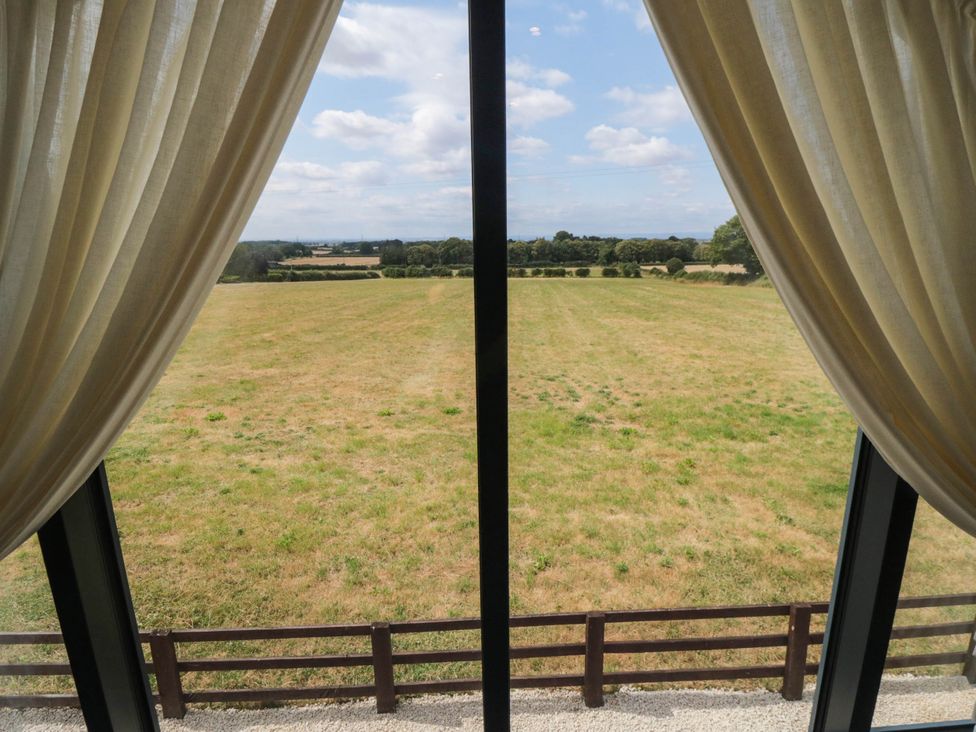 A view of a field through a window with curtains at Westholme Lodge in Thirsk
