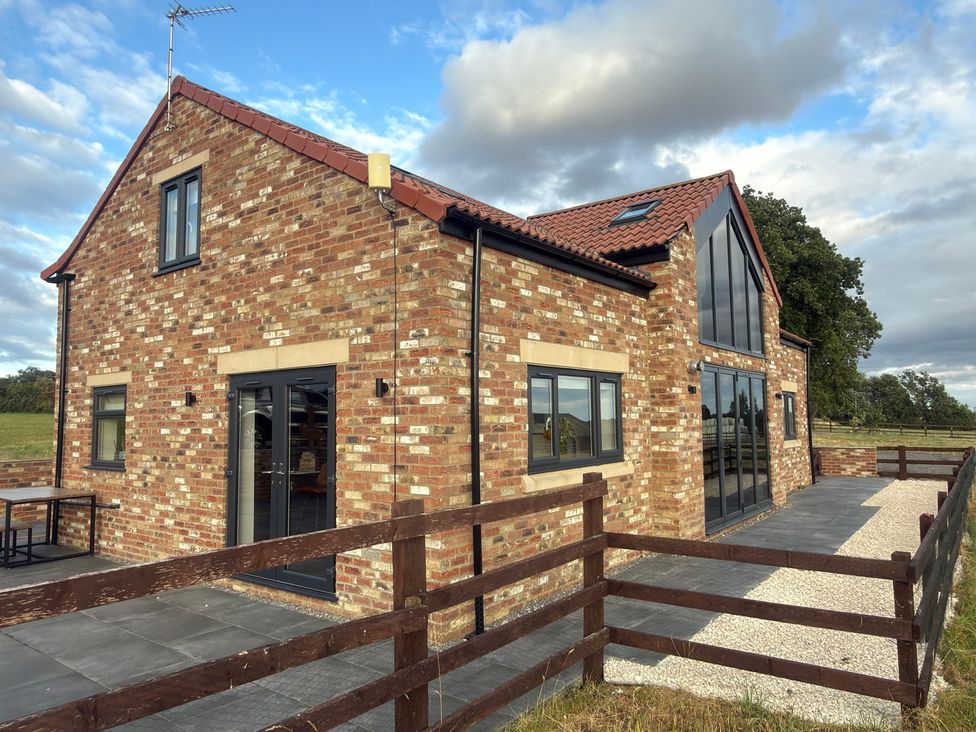 A house with brick exterior and patio at Westholme Country Lodge Thirsk