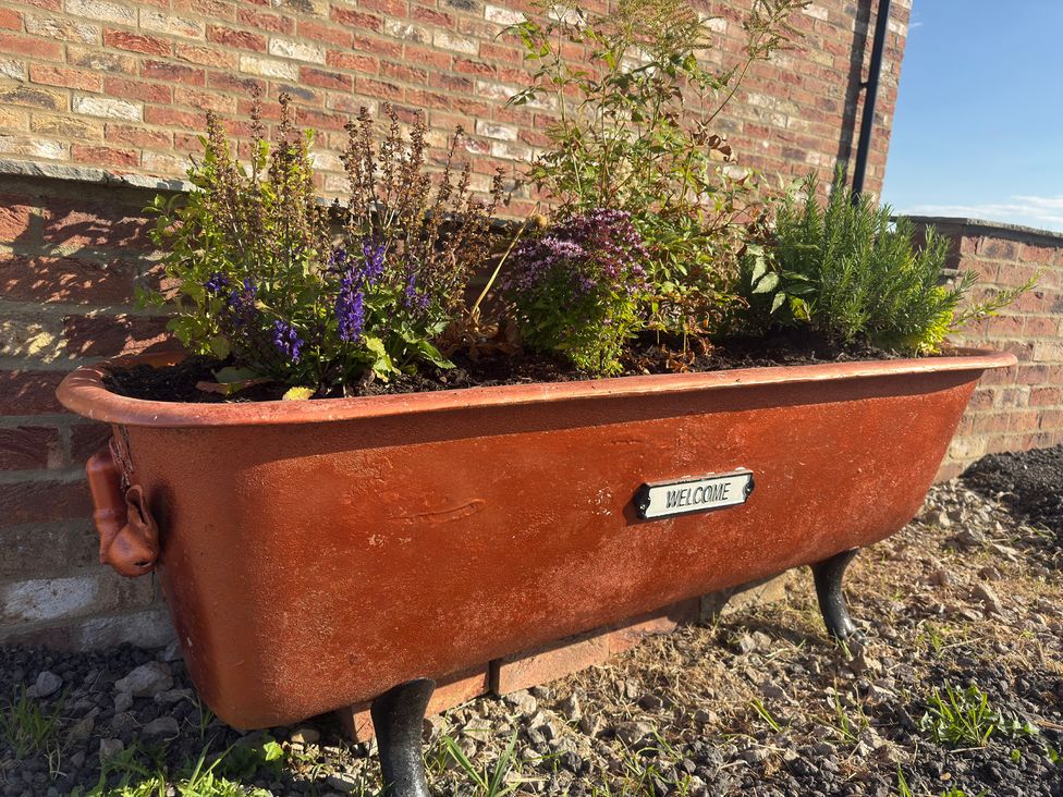 A planter filled with flowers sitting against a brick wall at Westholme Country Lodge in Thirsk