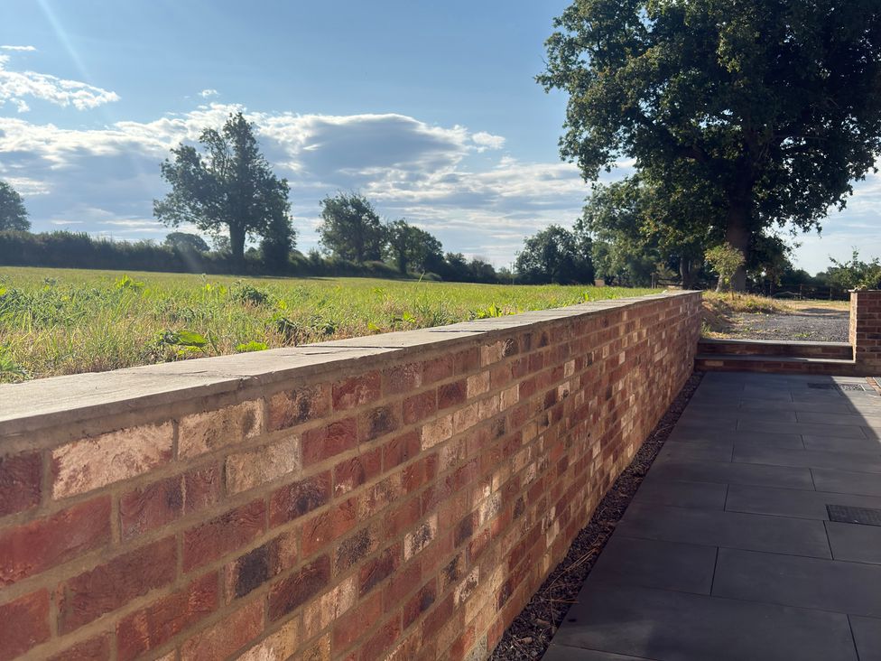 A brick wall with trees and grass in view at Westholme Country Lodge Thirsk
