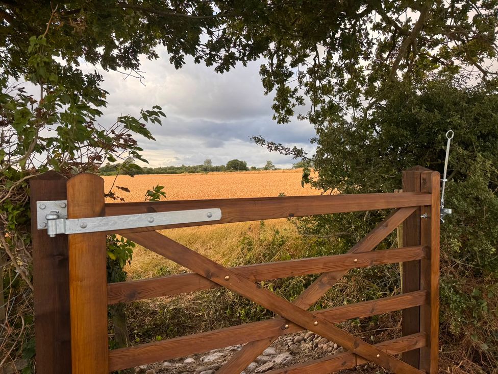 A wooden gate opening to a field at Westholme Country Lodge in Thirsk
