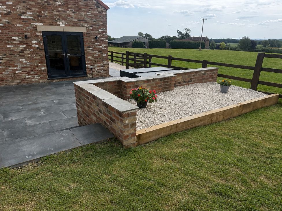 An outdoor area with a brick wall and a slate patio at Westholme Country Lodge Thirsk