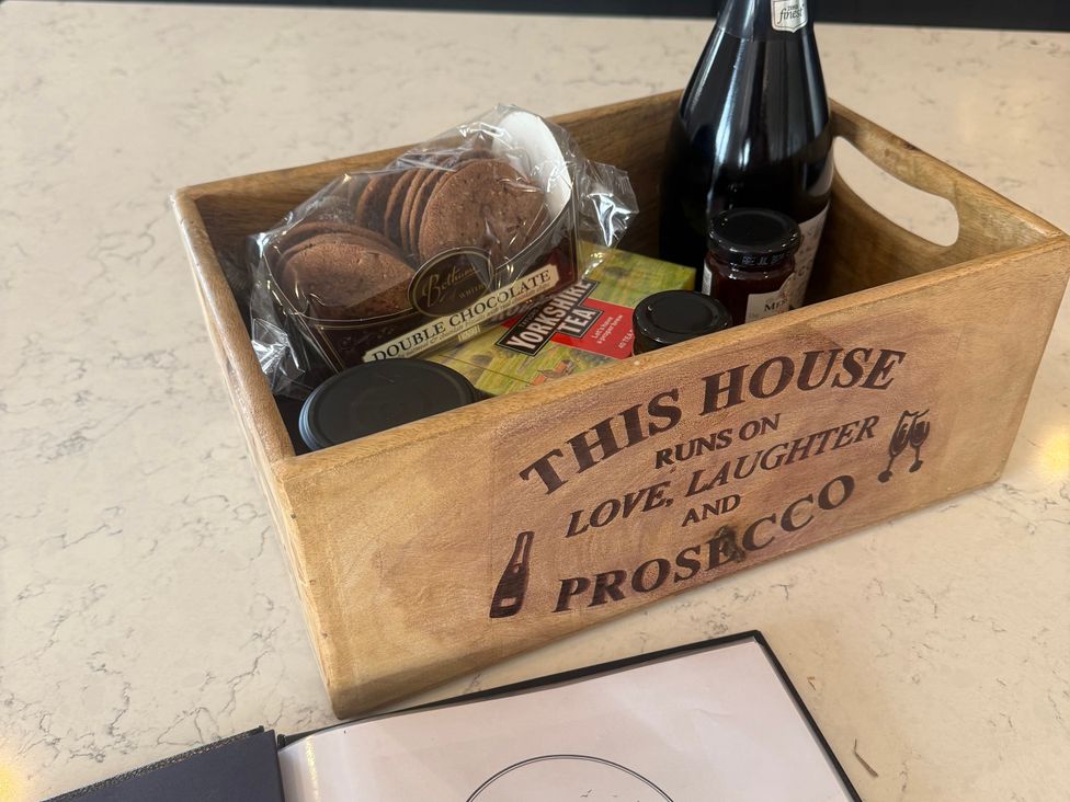 A wooden tray with cookies, tea, and a bottle of prosecco at Westholme Country Lodge in Thirsk