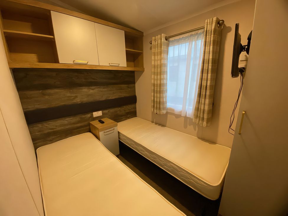 A bedroom with two beds and a window at Thameside Allhallows