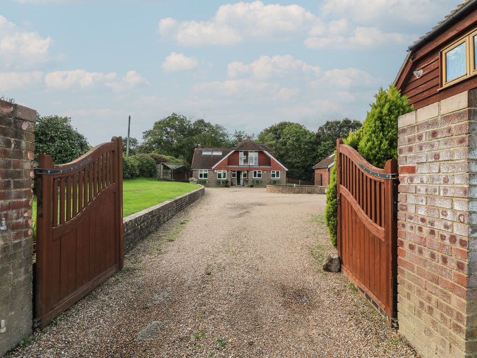 An outdoor view of a house with a gravel driveway and gate at Panel Place near Pett