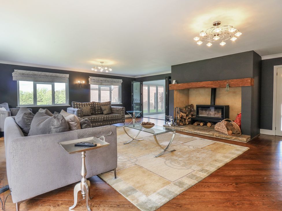 A living room with a fireplace and large windows at Panel Place near Pett