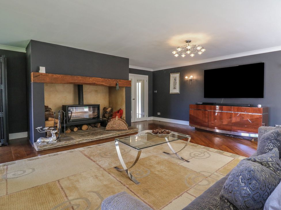A living room with a fireplace and glass table at Panel Place near Pett