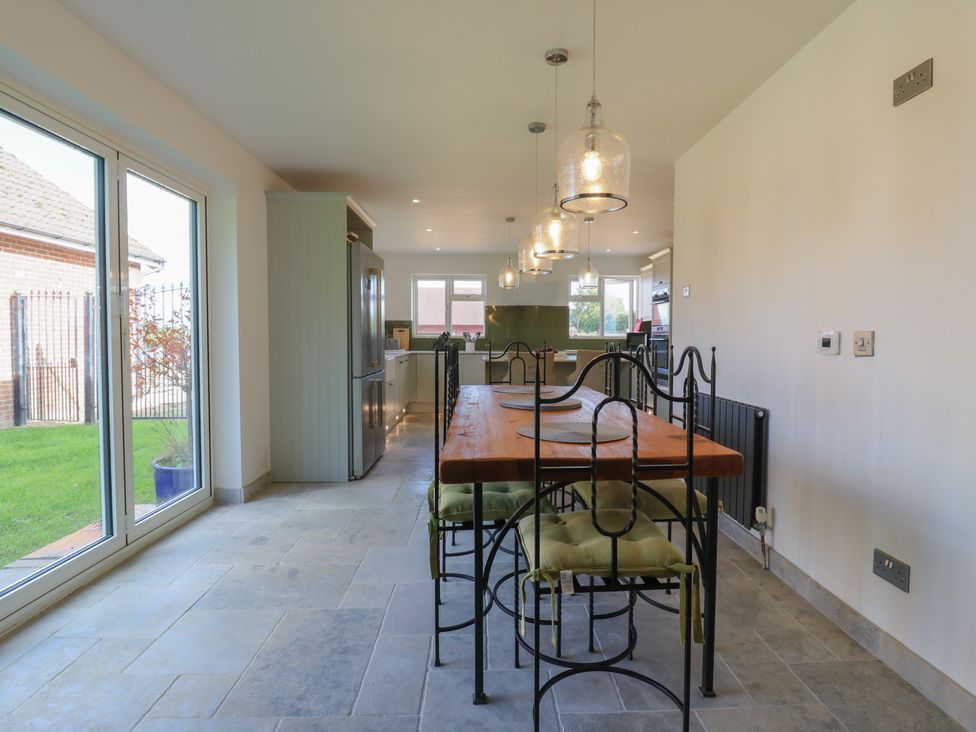 A kitchen with a wooden table and refrigerator at Panel Place near Pett