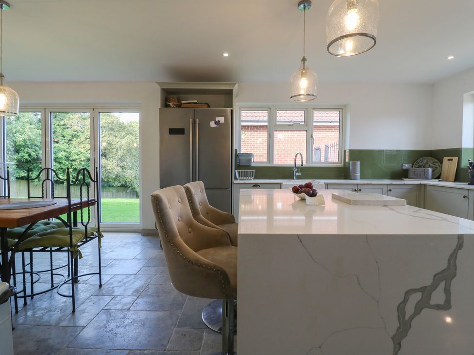 A kitchen with a refrigerator and island at Panel Place near Pett