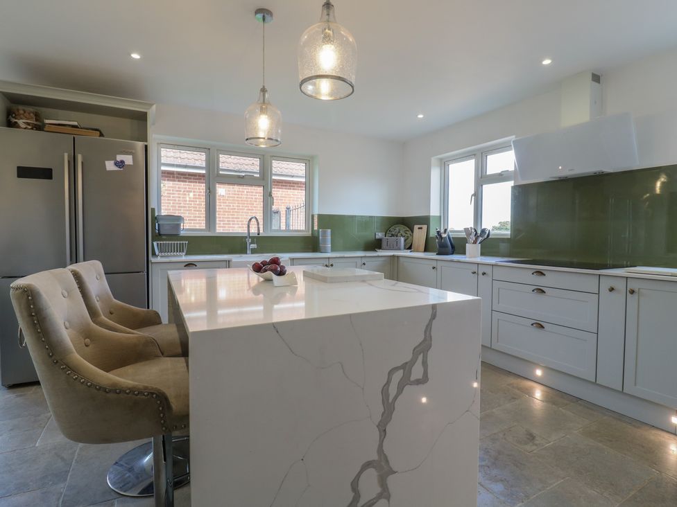 A kitchen with a countertop and bar stools at Panel Place near Pett