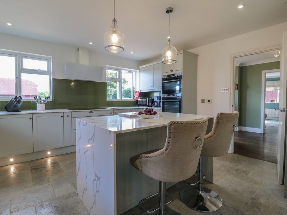 A kitchen with an island and bar stools at Panel Place near Pett
