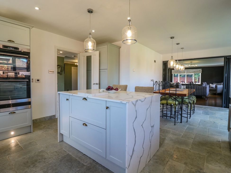 A kitchen with an island and dining table at Panel Place near Pett