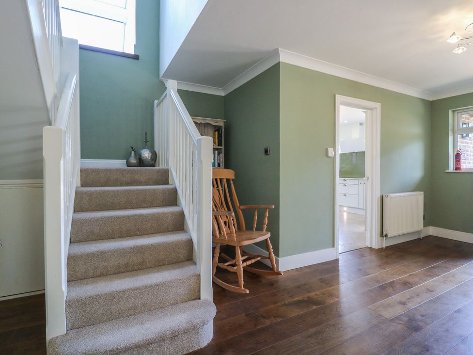 A hallway with a staircase and rocking chair at Panel Place near Pett