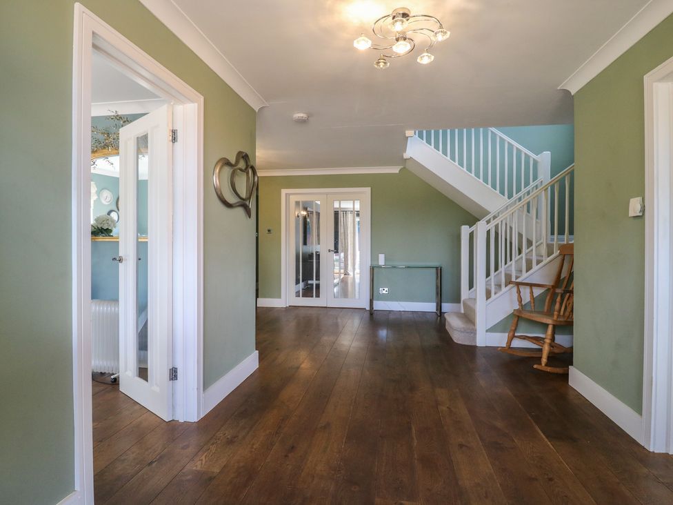 A hallway with a staircase and rocking chair at Panel Place near Pett