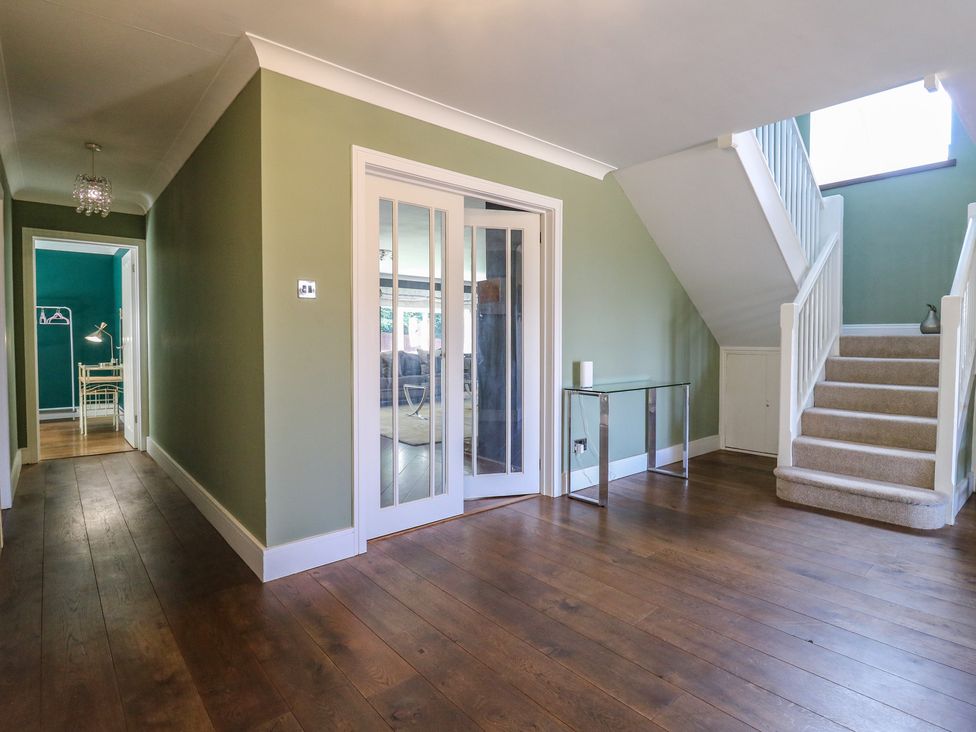 A hallway with a staircase and glass door at Panel Place near Pett