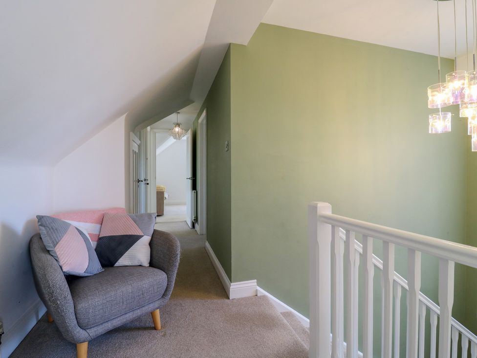 A hallway with an armchair and chandelier at Panel Place near Pett