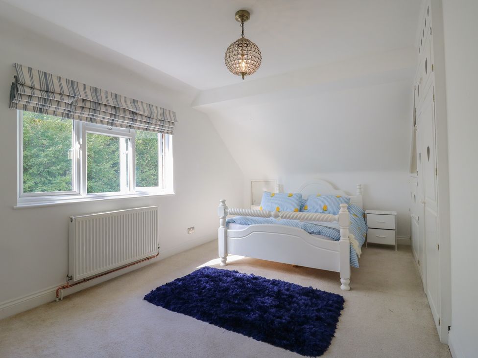 A bedroom with a bed and windows at Panel Place near Pett