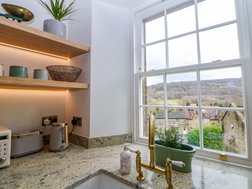 A kitchen with countertops, shelves, and a window view at The Reading Room in Hope Valley