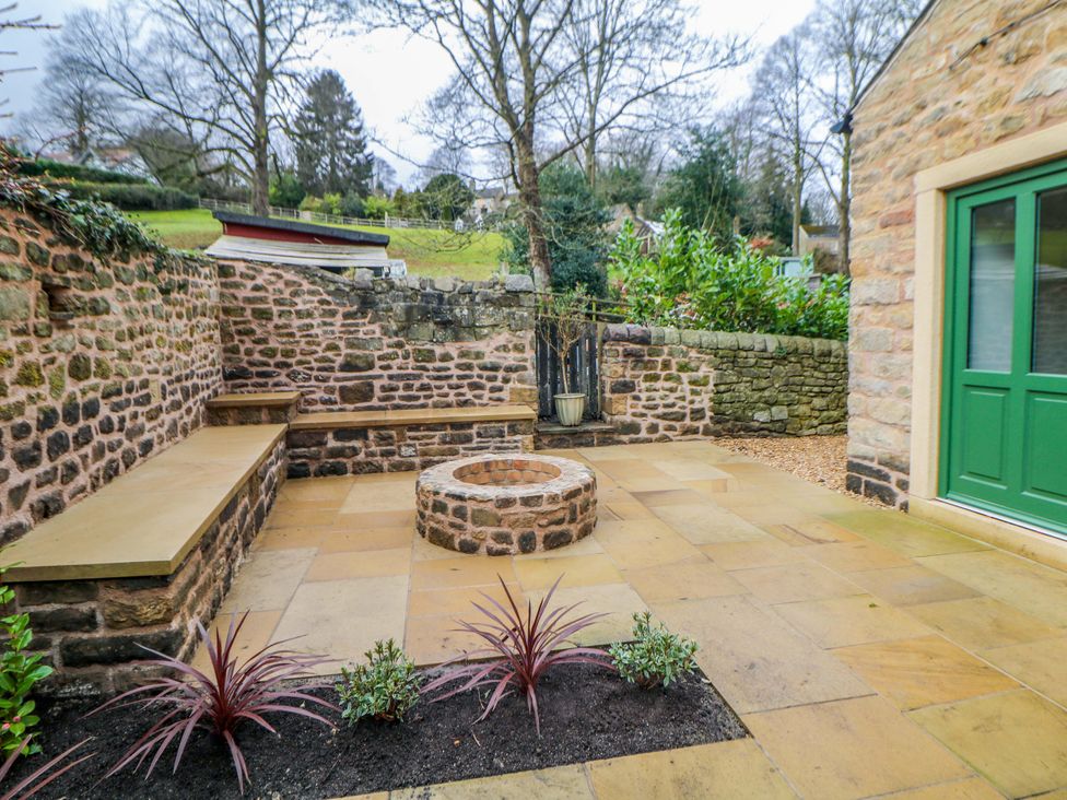 A garden with a stone wall and fire pit at The Reading Room Hope Valley