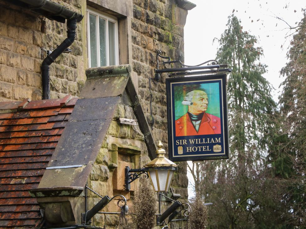 A hotel sign with the name Sir William Hotel on a stone building at The Reading Room in Hope Valley
