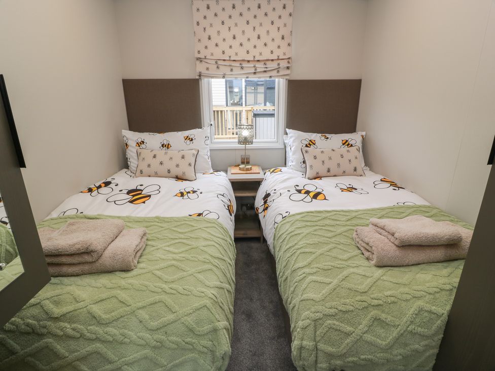A bedroom with two beds and a bedside table at Willow's Way in Stranraer