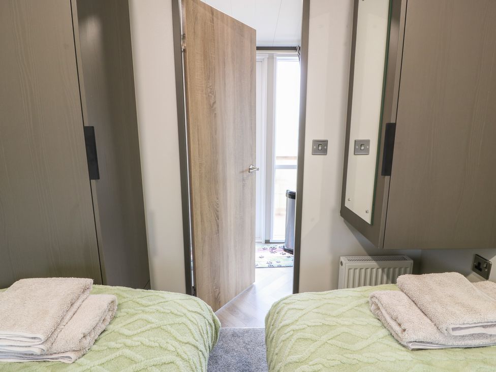 A bedroom with beds and a door leading to another area at Willow's Way in Stranraer