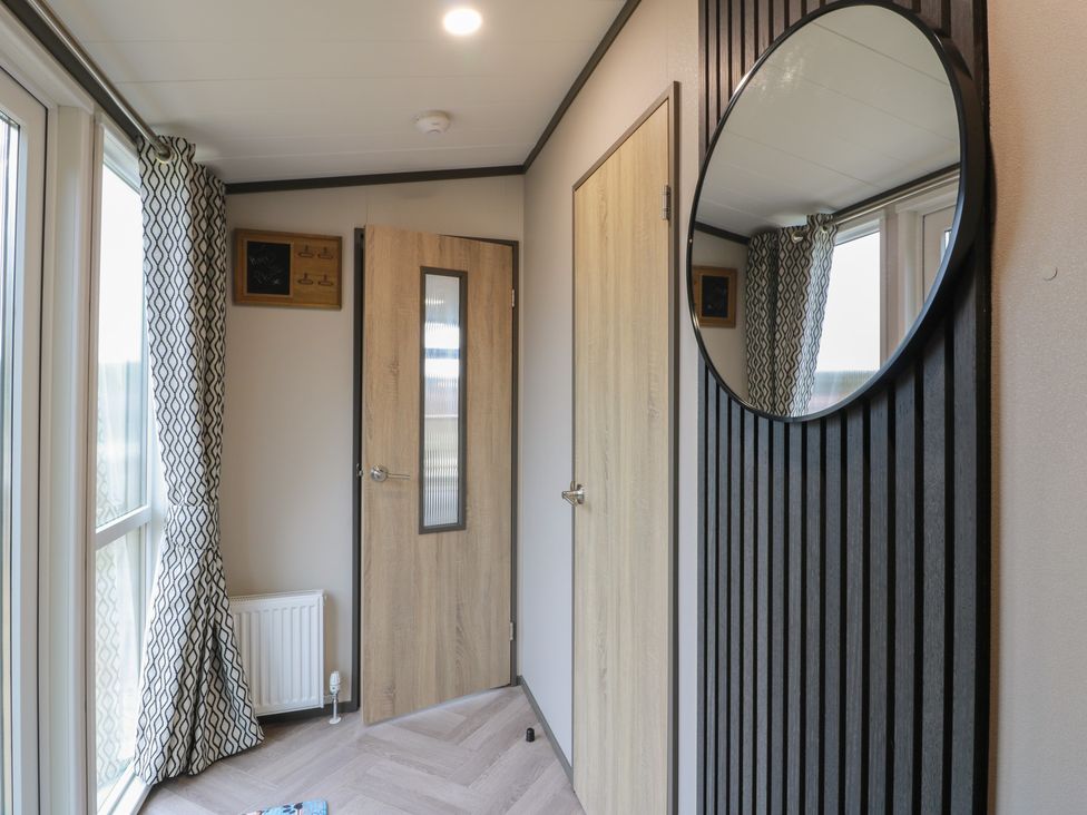 A hallway with a door and mirror at Willow's Way in Stranraer