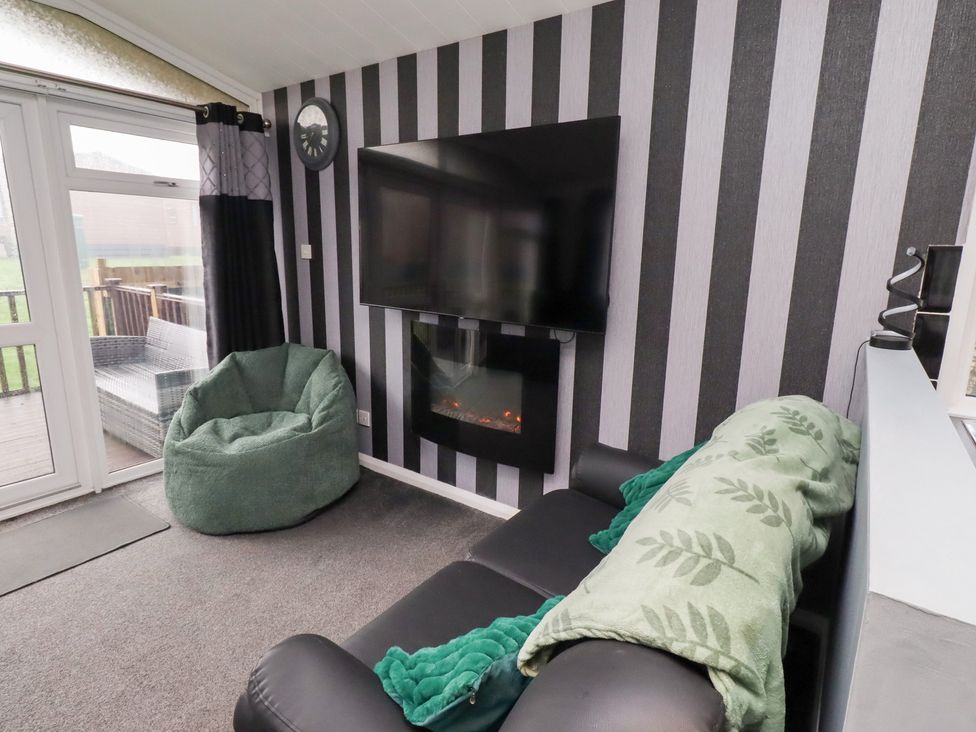 A living room with a television and a bean bag at Harper's Hideaway, Felmoor Holiday Park near Felton