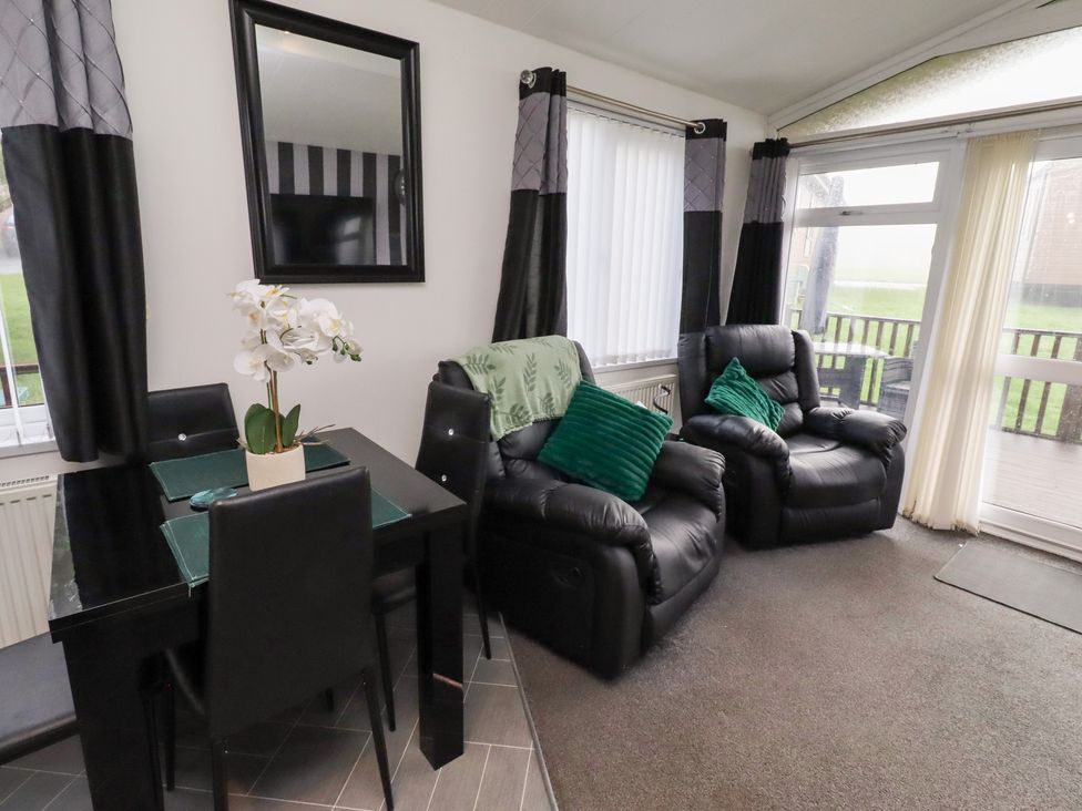 A living room with a dining table and chairs at Harper's Hideaway near Felmoor Holiday Park
