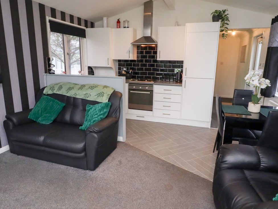 A living room with a sofa and kitchen area at Harper's Hideaway Felmoor Holiday Park near Felton