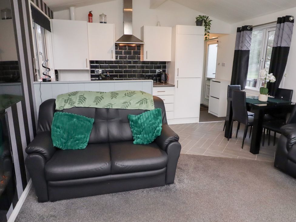 A living room with a sofa and kitchen area at Harper's Hideaway near Felmoor Holiday Park near Felton