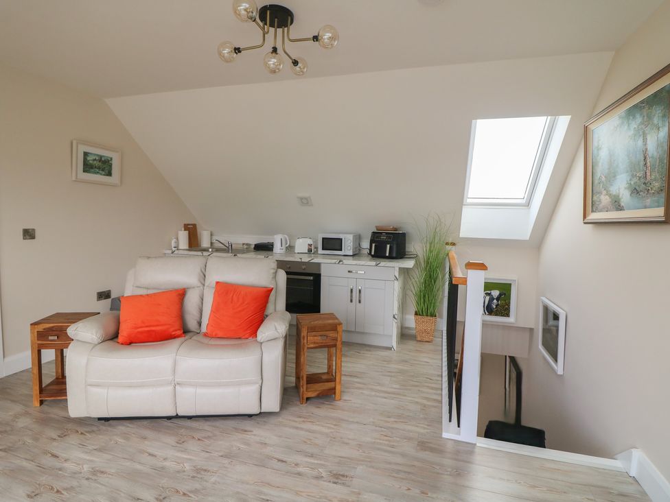 A living room with a sofa and kitchen appliances at Ard Uisce @ Estuary Bliss, Duncannon, County Wexford